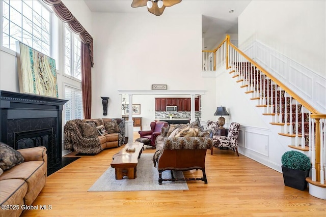 living room featuring ceiling fan, a tile fireplace, and light wood-type flooring