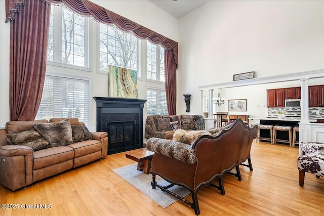 living room with plenty of natural light, light hardwood / wood-style floors, and a high ceiling