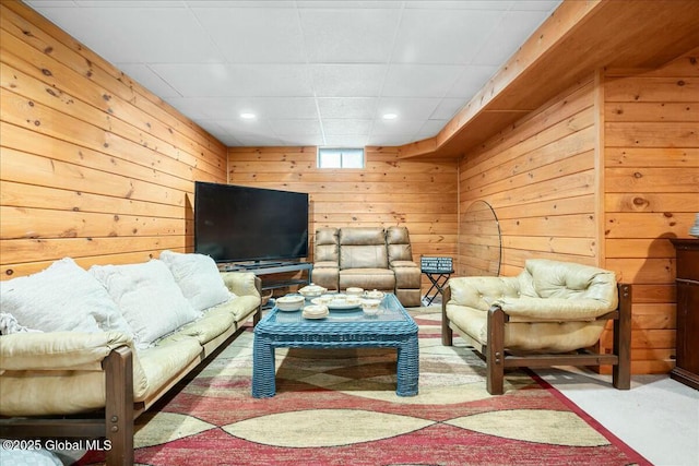 living room with carpet flooring, a drop ceiling, and wood walls