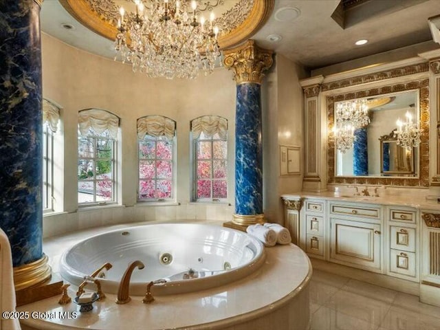 bathroom with a whirlpool tub, an inviting chandelier, ornate columns, and vanity