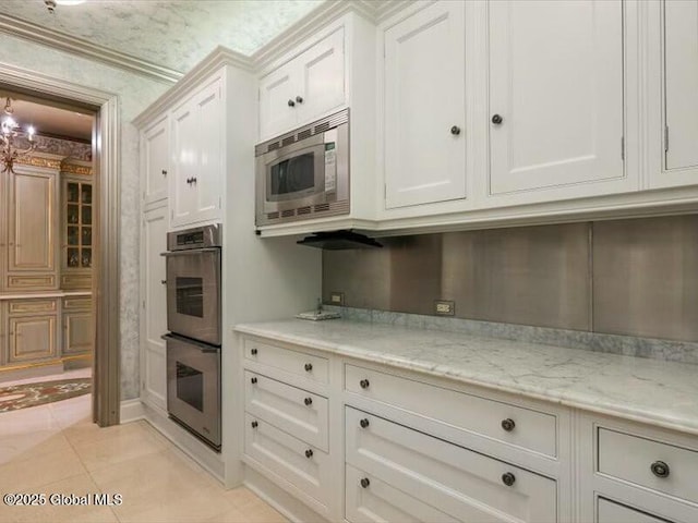 kitchen featuring light tile patterned floors, stainless steel appliances, light stone countertops, and white cabinets