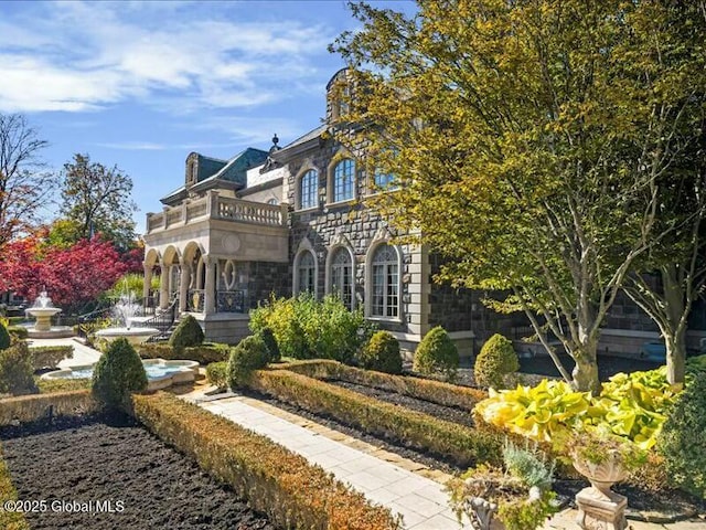 view of front facade featuring stone siding and a balcony