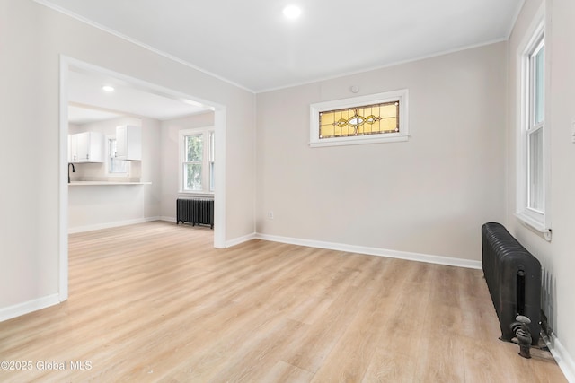 living area featuring ornamental molding, radiator, baseboards, and light wood-type flooring