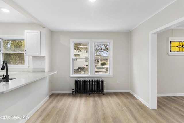 unfurnished dining area with light wood-type flooring, baseboards, and radiator