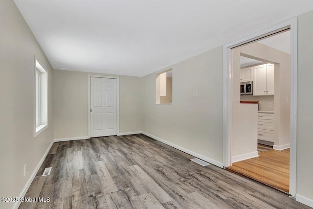 unfurnished room with visible vents, baseboards, and wood finished floors