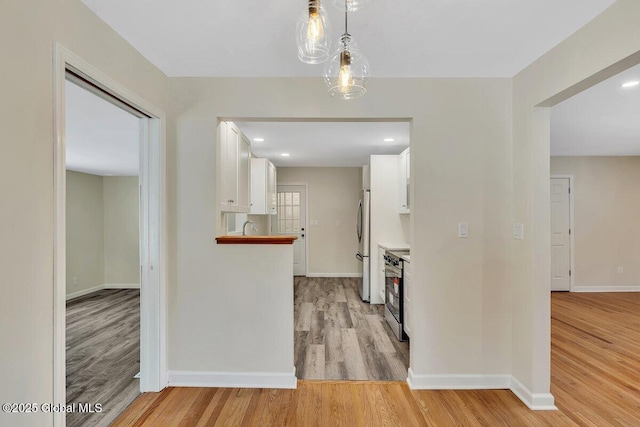 corridor featuring recessed lighting, baseboards, light wood-style floors, and a sink