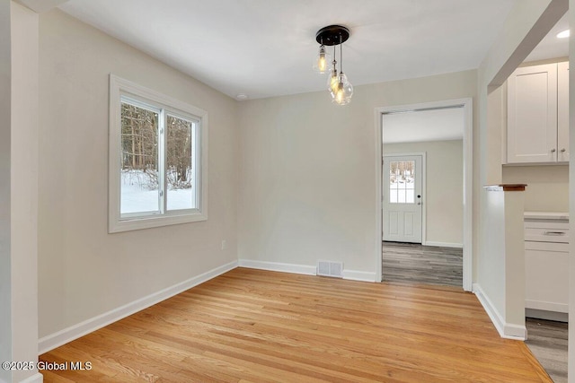 unfurnished dining area featuring visible vents, baseboards, and light wood-style floors