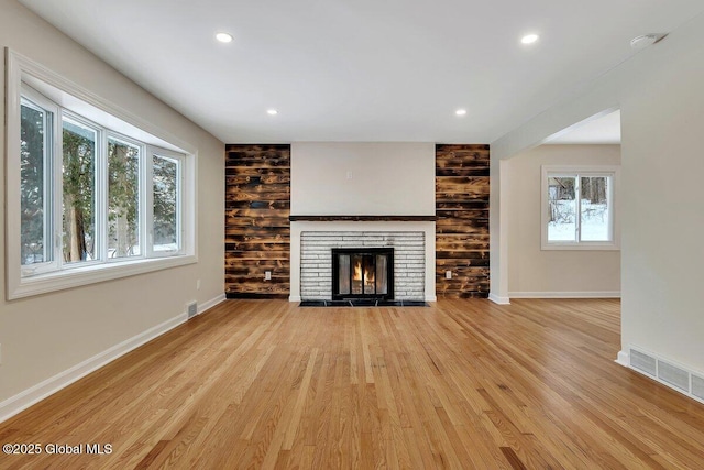 unfurnished living room featuring wood finished floors, a fireplace, visible vents, and baseboards