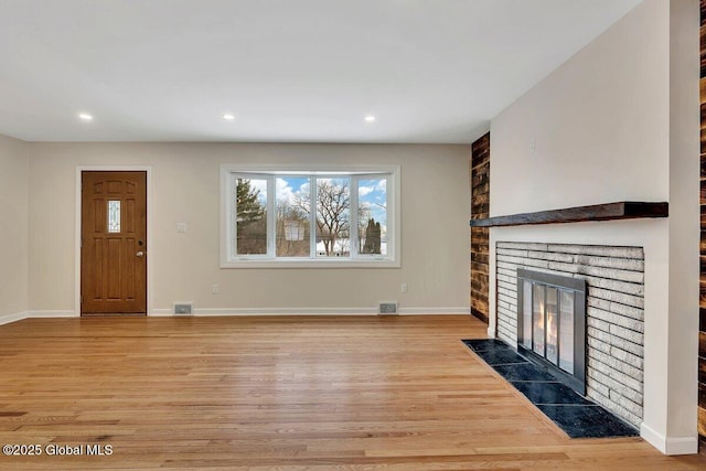 unfurnished living room featuring a brick fireplace, baseboards, and light wood-style floors