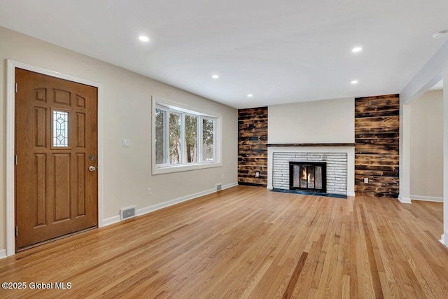 unfurnished living room with baseboards, a healthy amount of sunlight, a glass covered fireplace, and light wood finished floors