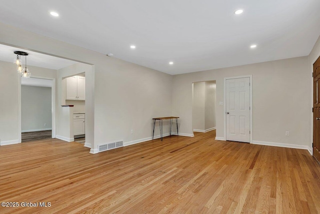 spare room featuring light wood finished floors, visible vents, recessed lighting, and baseboards