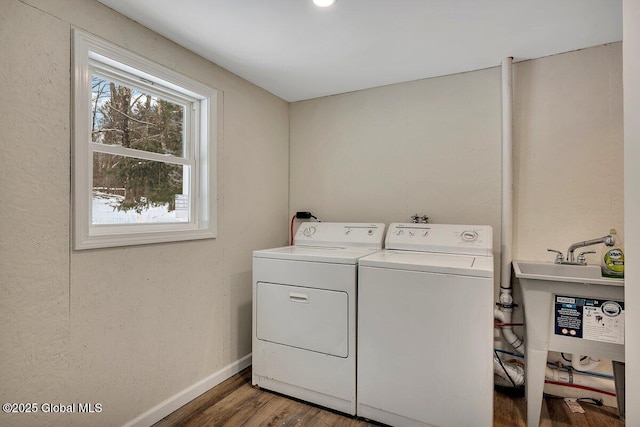 laundry room with wood finished floors, baseboards, washing machine and clothes dryer, laundry area, and a sink