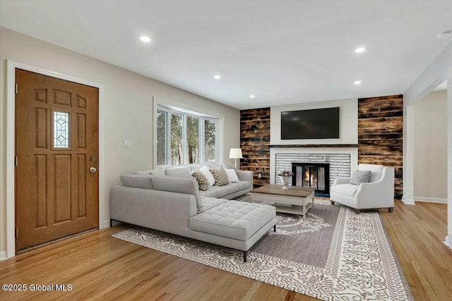 living room featuring plenty of natural light, recessed lighting, light wood-style floors, and a glass covered fireplace