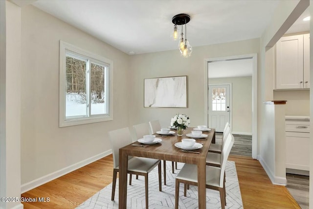 dining space featuring light wood-type flooring and baseboards