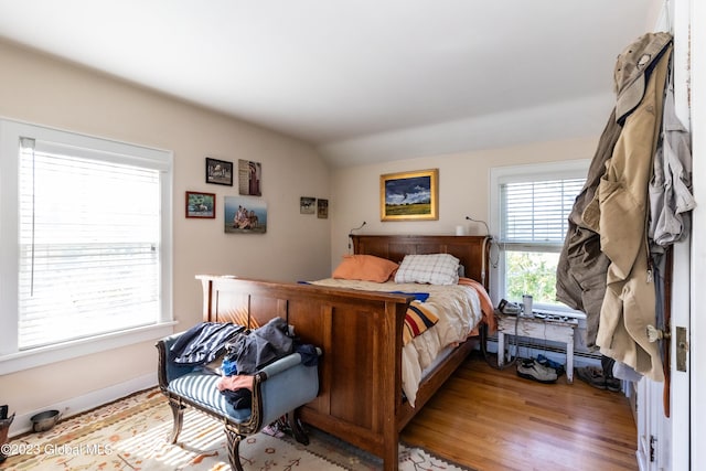 bedroom featuring lofted ceiling, a baseboard heating unit, and light hardwood / wood-style floors