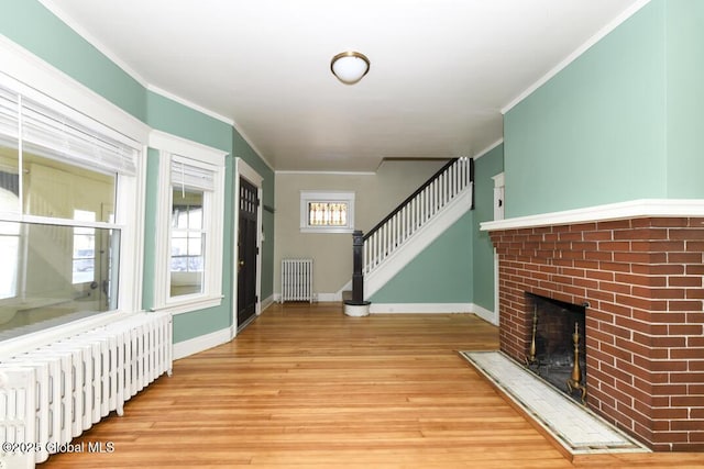 foyer with a brick fireplace, crown molding, and radiator heating unit