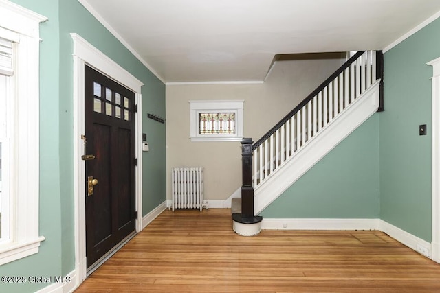 entrance foyer with radiator, ornamental molding, and light hardwood / wood-style floors