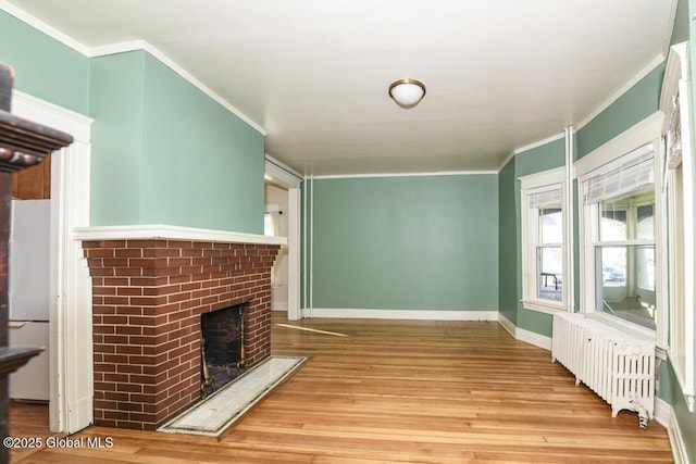 unfurnished living room with radiator, a fireplace, light hardwood / wood-style floors, and ornamental molding