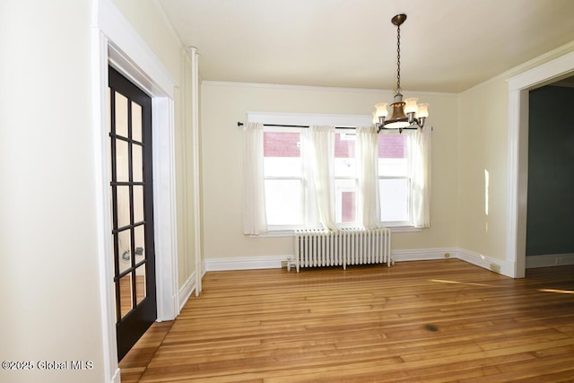 unfurnished dining area featuring an inviting chandelier, radiator, crown molding, and hardwood / wood-style floors