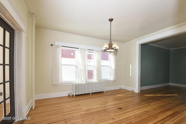 unfurnished dining area featuring crown molding, radiator, hardwood / wood-style floors, and an inviting chandelier