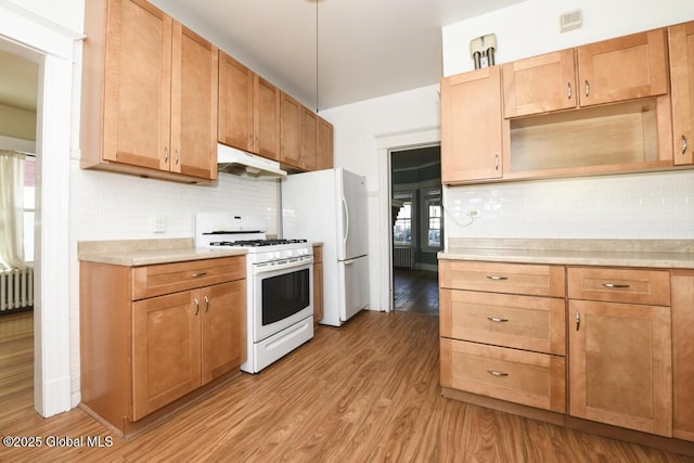 kitchen featuring radiator heating unit, tasteful backsplash, hanging light fixtures, gas range gas stove, and light hardwood / wood-style flooring