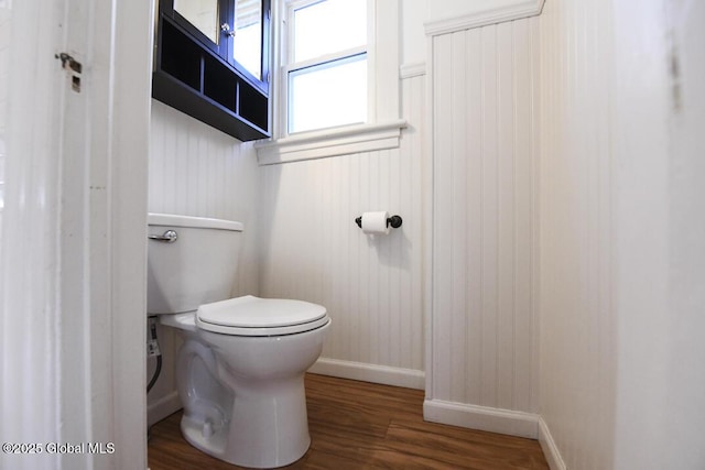 bathroom with hardwood / wood-style floors, wood walls, and toilet