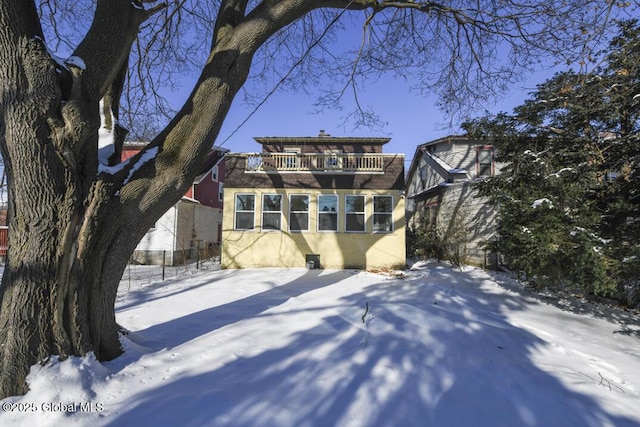 snow covered back of property with a balcony