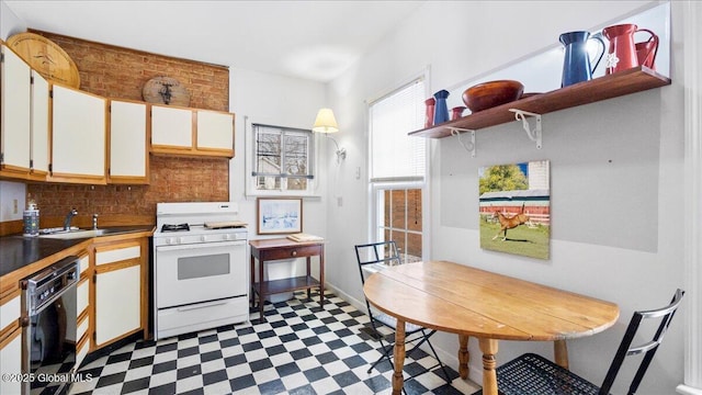 kitchen featuring sink, backsplash, black dishwasher, white cabinets, and white range with gas cooktop