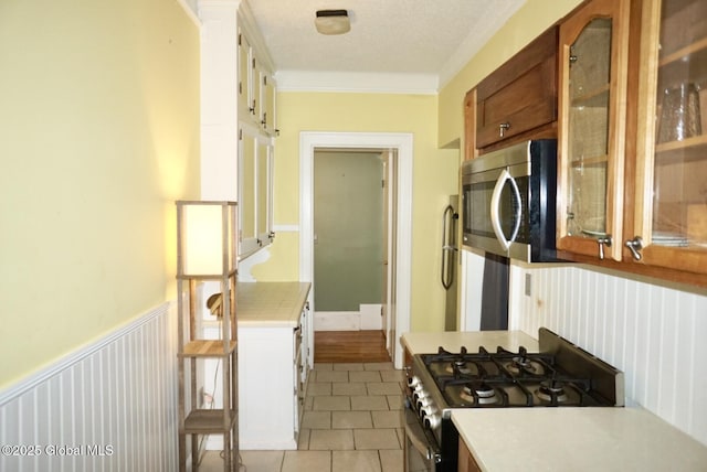 kitchen featuring crown molding, stainless steel appliances, a textured ceiling, and light tile patterned floors