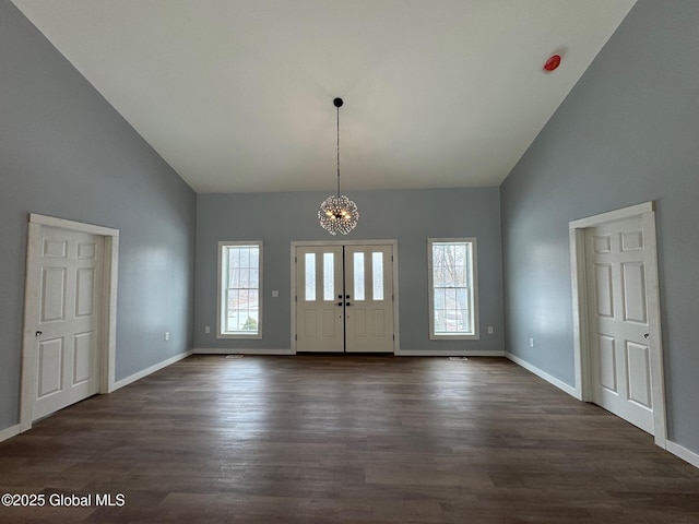 foyer entrance featuring an inviting chandelier, dark wood-type flooring, and a high ceiling