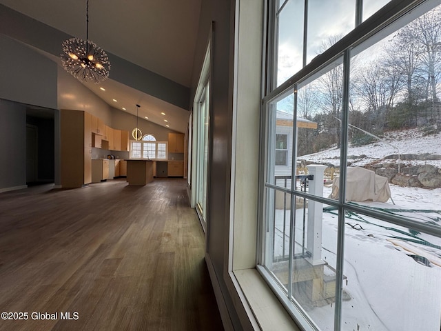 corridor featuring dark hardwood / wood-style flooring, a notable chandelier, and high vaulted ceiling