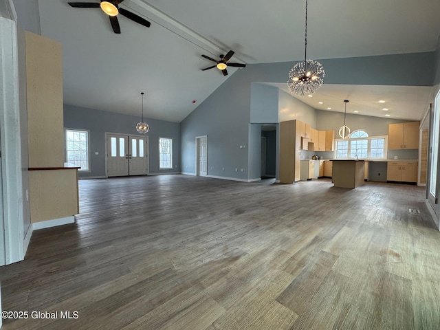 unfurnished living room with dark hardwood / wood-style flooring, ceiling fan with notable chandelier, and high vaulted ceiling