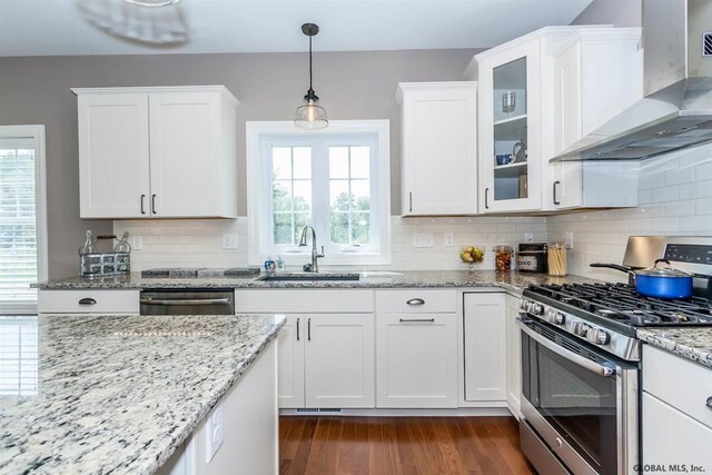 kitchen with white cabinetry, appliances with stainless steel finishes, sink, and wall chimney range hood