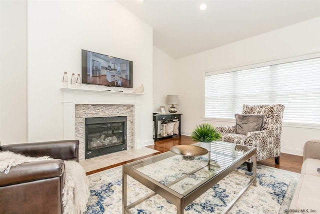 living room with vaulted ceiling, hardwood / wood-style floors, and a fireplace