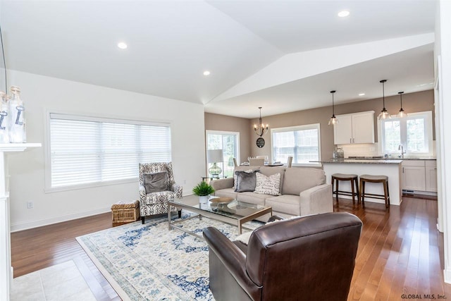living room with an inviting chandelier, sink, vaulted ceiling, and dark hardwood / wood-style floors