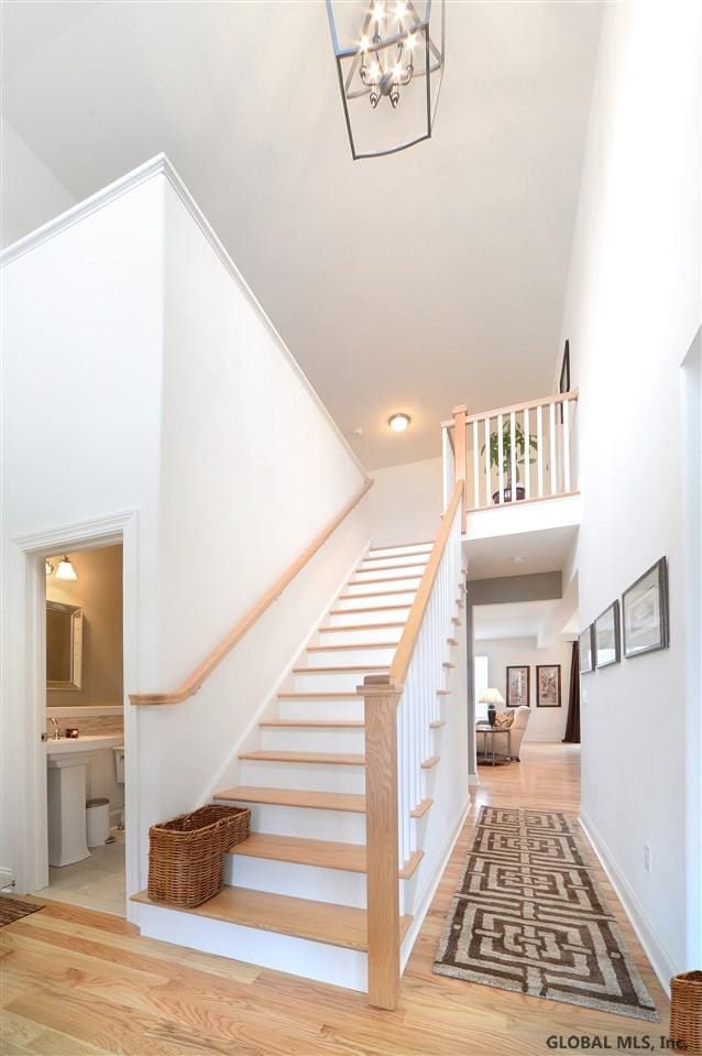 staircase featuring hardwood / wood-style flooring, a towering ceiling, and a notable chandelier