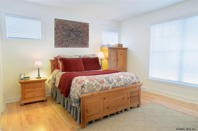 bedroom with multiple windows and light hardwood / wood-style flooring