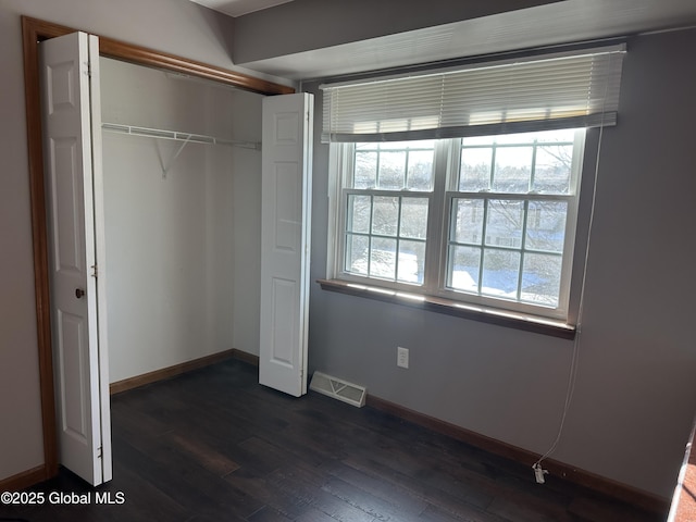 unfurnished bedroom with a closet and dark hardwood / wood-style floors