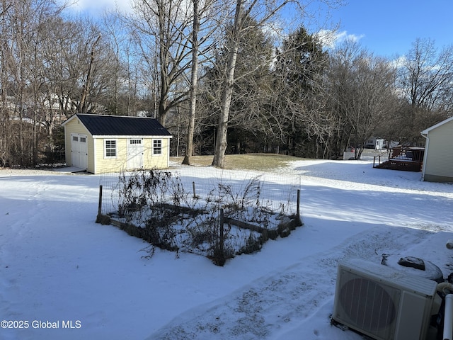 yard layered in snow featuring a garage, an outdoor structure, and ac unit