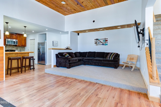 living room with wood ceiling, a towering ceiling, and light wood-type flooring