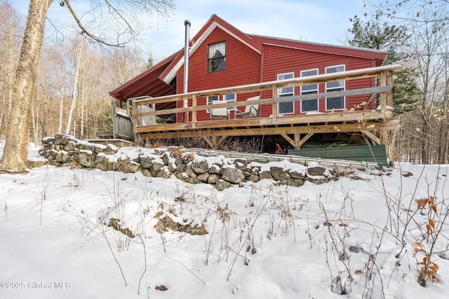 snow covered rear of property with a wooden deck