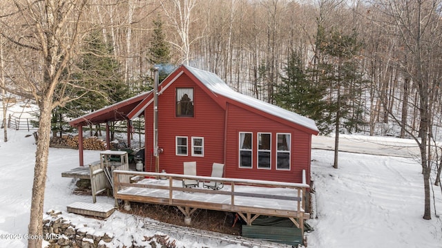 snow covered back of property featuring a deck