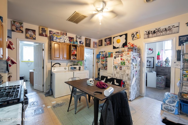 kitchen featuring plenty of natural light, refrigerator, washer and dryer, and stainless steel gas range oven