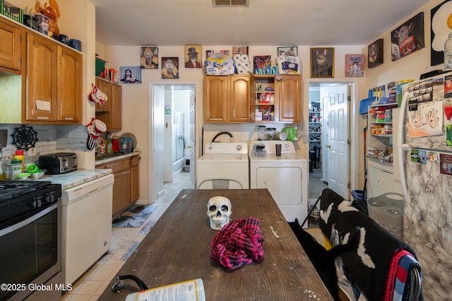 kitchen featuring light tile patterned floors, dishwasher, backsplash, separate washer and dryer, and gas range