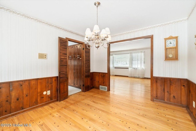 empty room with an inviting chandelier and light wood-type flooring