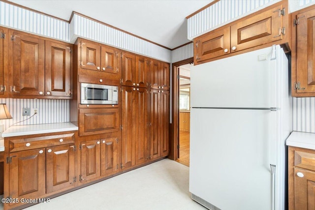 kitchen with stainless steel microwave, ornamental molding, and white fridge