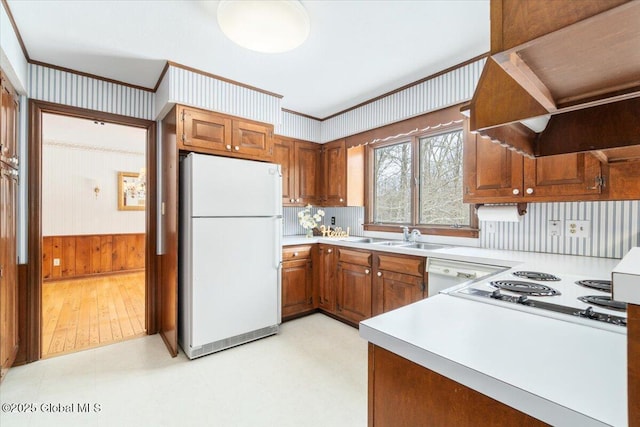 kitchen with premium range hood, sink, wood walls, ornamental molding, and white appliances