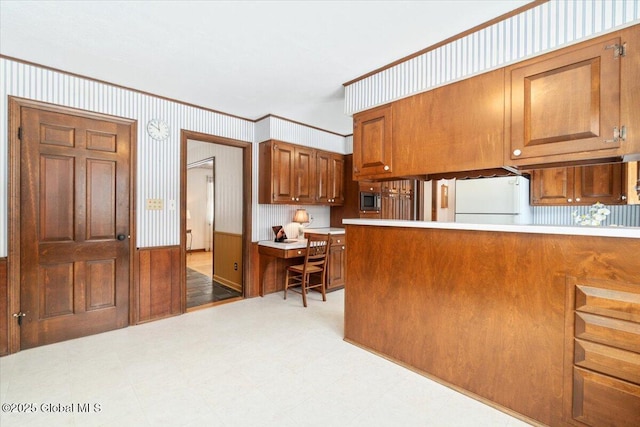 kitchen featuring white refrigerator, stainless steel microwave, and kitchen peninsula