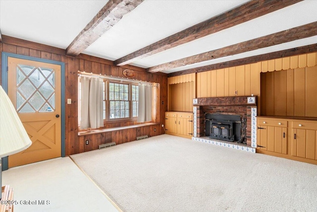 unfurnished living room with beamed ceiling, carpet floors, and wooden walls