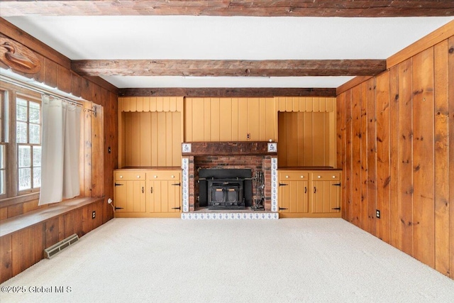 unfurnished living room with light colored carpet, wooden walls, and beam ceiling